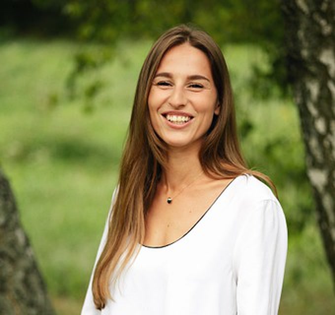 Karolina Ponichtera, uśmiechnięta, na tle zieleni